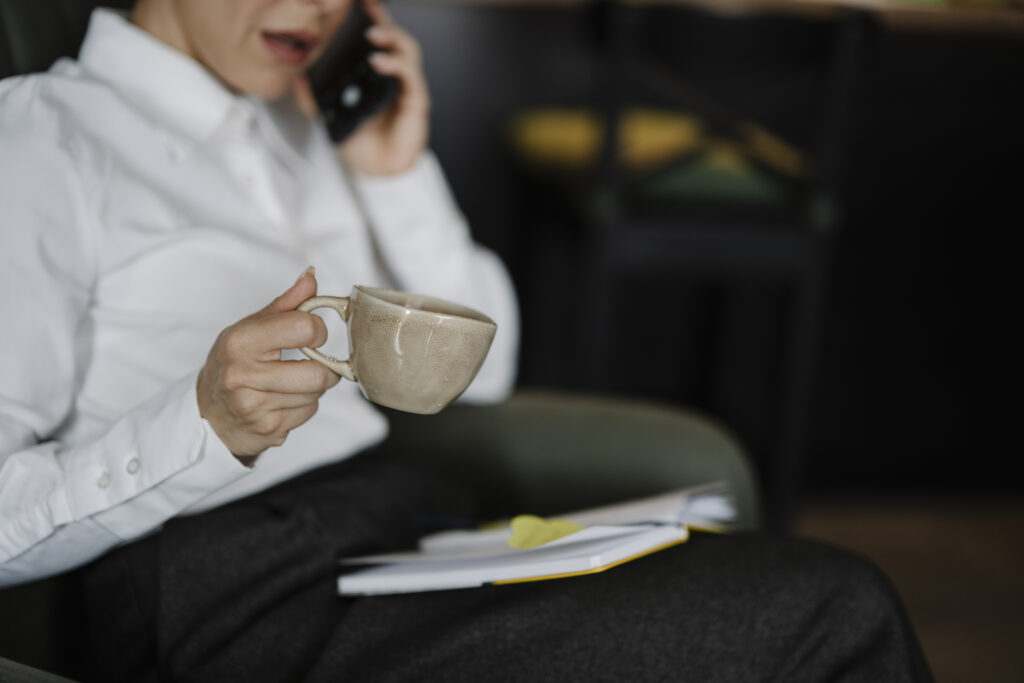 Người đang trao đổi qua điện thoại, bên cạnh là sổ ghi chép